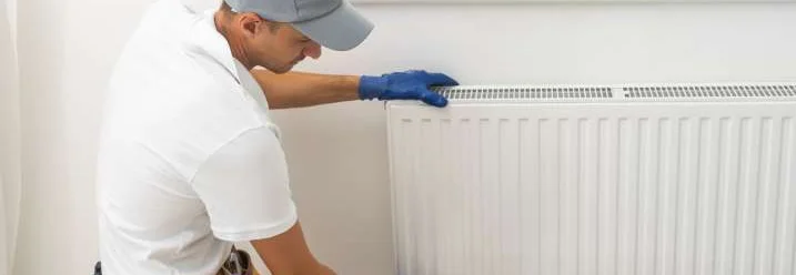 Eine Person montiert einen weißen Heizkörper an einer Wand.